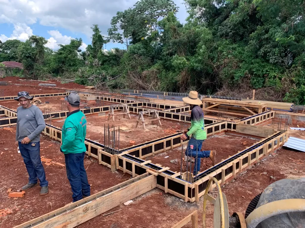 Operários trabalhando na armação de fundação de baldrame em terreno de obra
