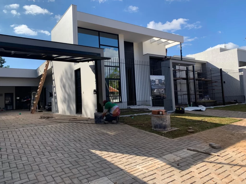 Casa moderna branca e preta com grandes panos de vidro na fase final da obra