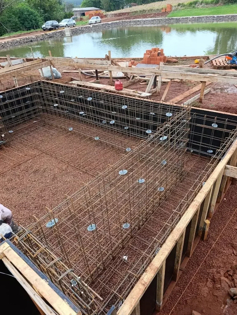 Armação de ferragem e formas de madeira para piscina de concreto à beira de um lago, obra