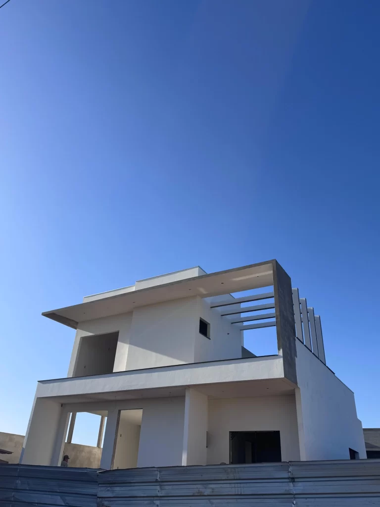 Sobrado branco em estrutura visto de baixo contra céu azul, residência em obra