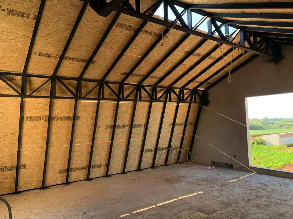 Interior de galpão com estrutura metálica e forro de OSB inclinado, contrapiso em obra