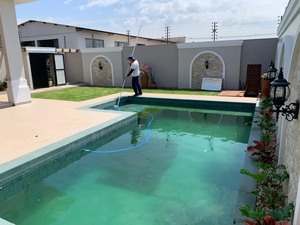 Funcionário limpando piscina de borda em pedra em área de lazer entregue