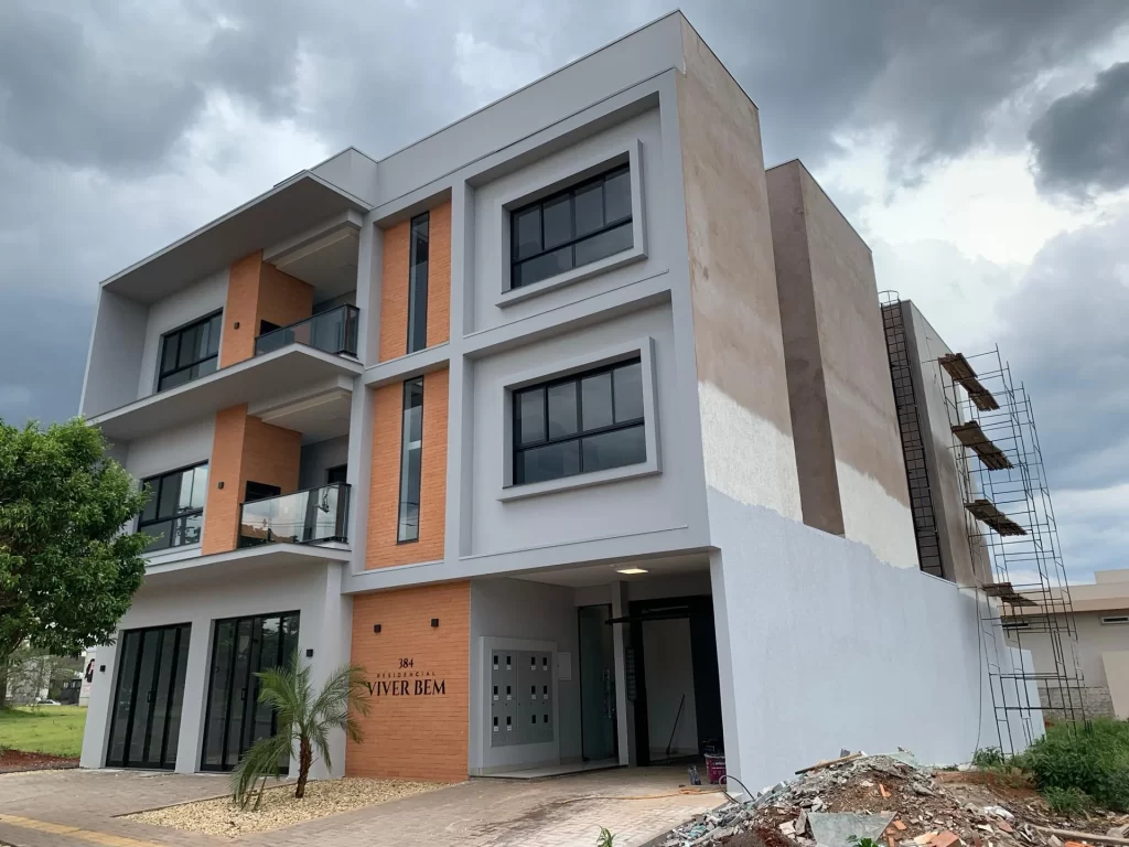 Residencial Viver Bem três pavimentos com fachada em tijolo, andaime e entulho na lateral