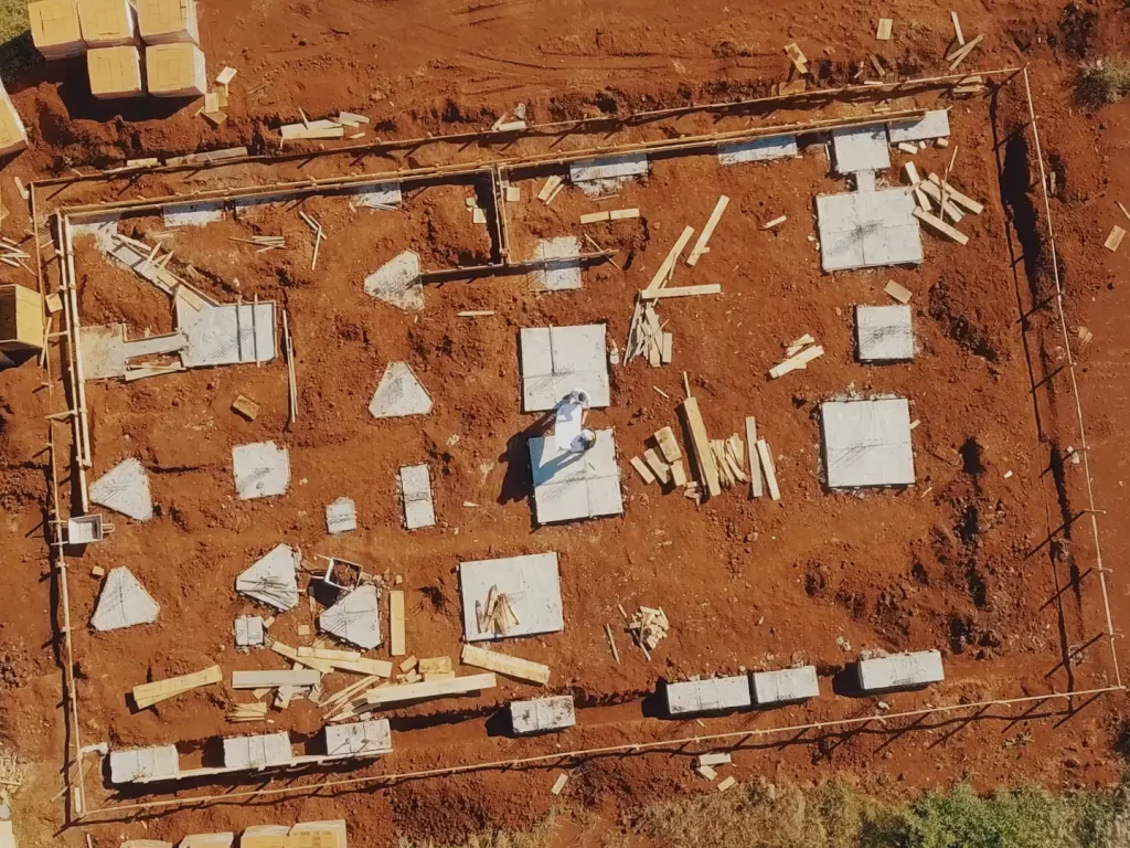 Vista aérea da locação de fundação com sapatas concretadas sobre terreno de terra vermelha
