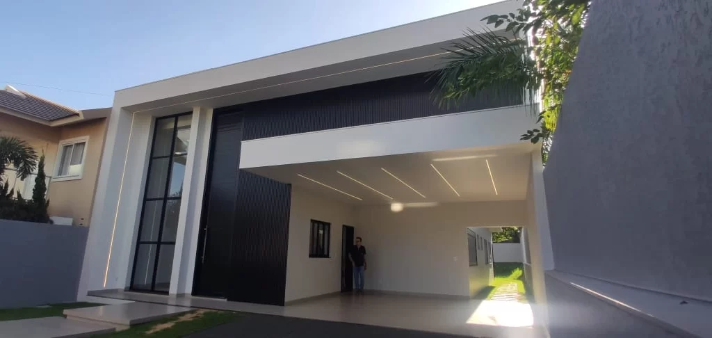 Residência moderna entregue com fachada em ripado preto, volumes brancos e garagem coberta